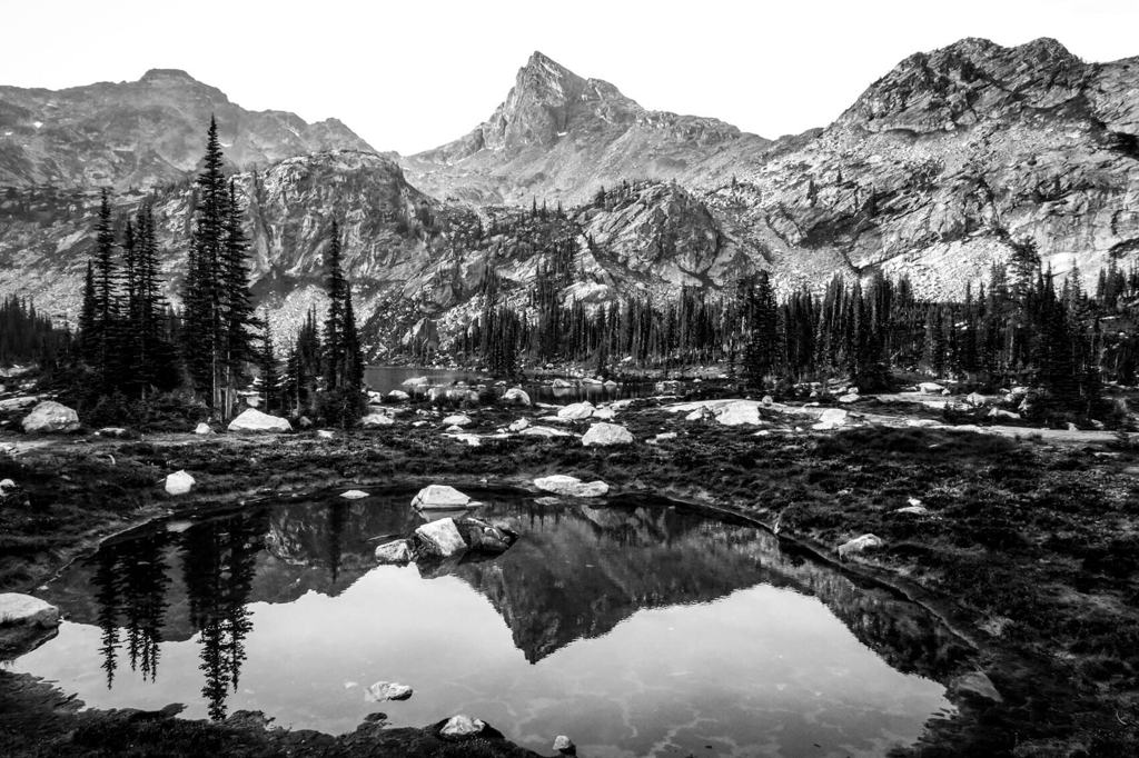 A mountain basin mirrored in a shallow tarn, in black and white
